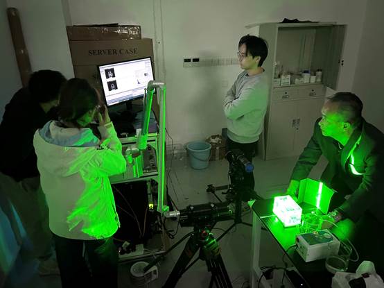 A group of people in a room with green light

Description automatically generated